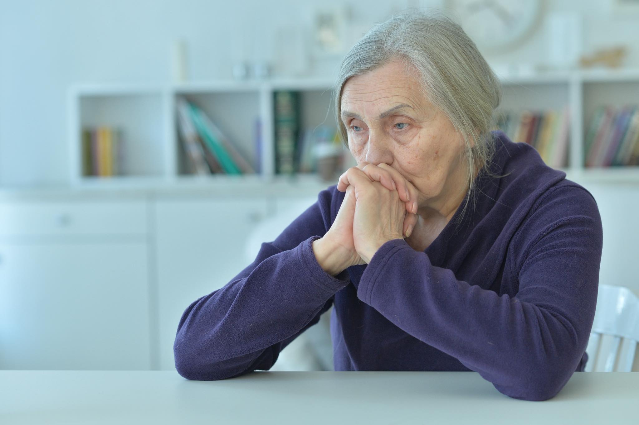 Close up portrait of sad  senior woman sitting at table